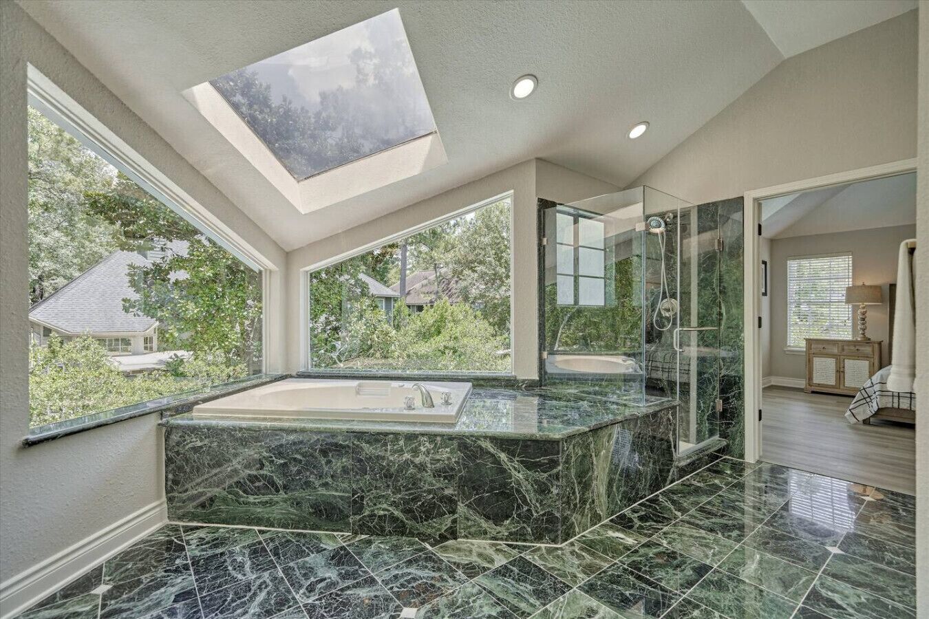 A spacious bathroom with a large skylight, a marble sink, and a glass-enclosed shower.
