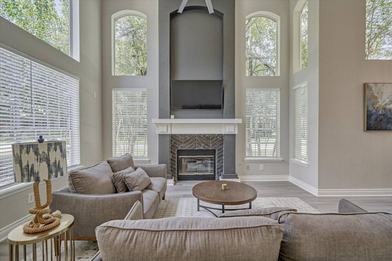 A spacious living room with a fireplace, comfortable seating, and large windows.