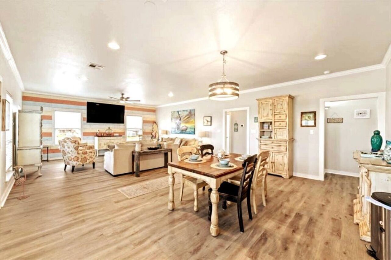 A spacious living area with a wooden dining table, chairs, and a television.