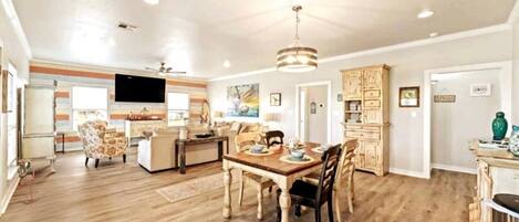 A spacious living area with a wooden dining table, chairs, and a television.