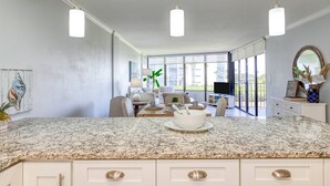 A spacious kitchen with granite countertops, white cabinets, and pendant lighting. - Beachfront Condo, Stunning Views, Pool, Fully Updated, Short Drive to Downtown, $300 in Free Tickets (St. Augustine)