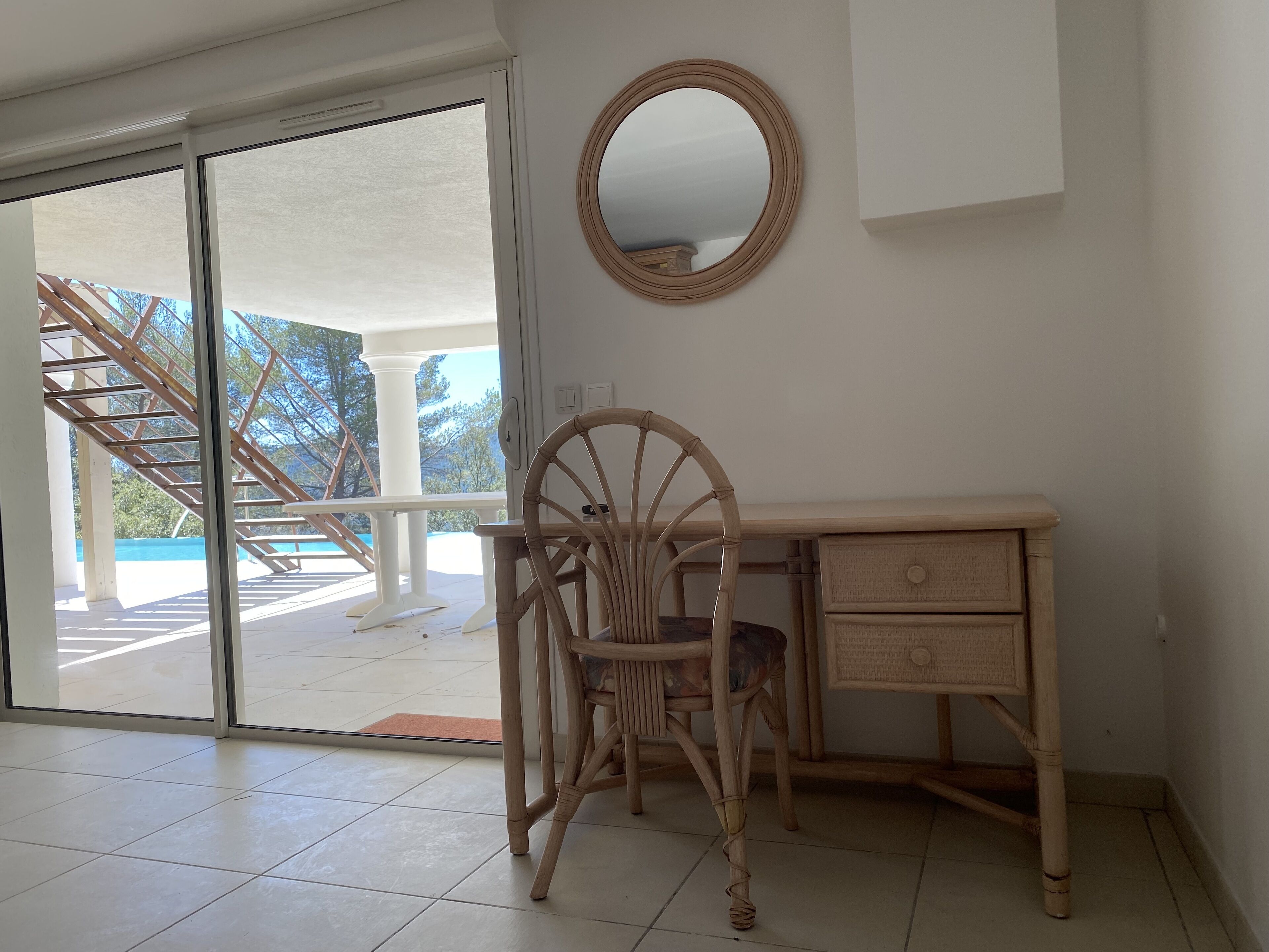 Una habitación con escritorio, silla y un espejo grande en la pared.