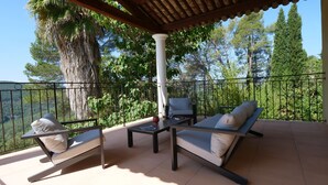 A terrace with a pergola, two lounge chairs, a small table, and a potted plant. - French Riviera Air-conditioned Villa with heated infinity pool, Amazing view (Var)