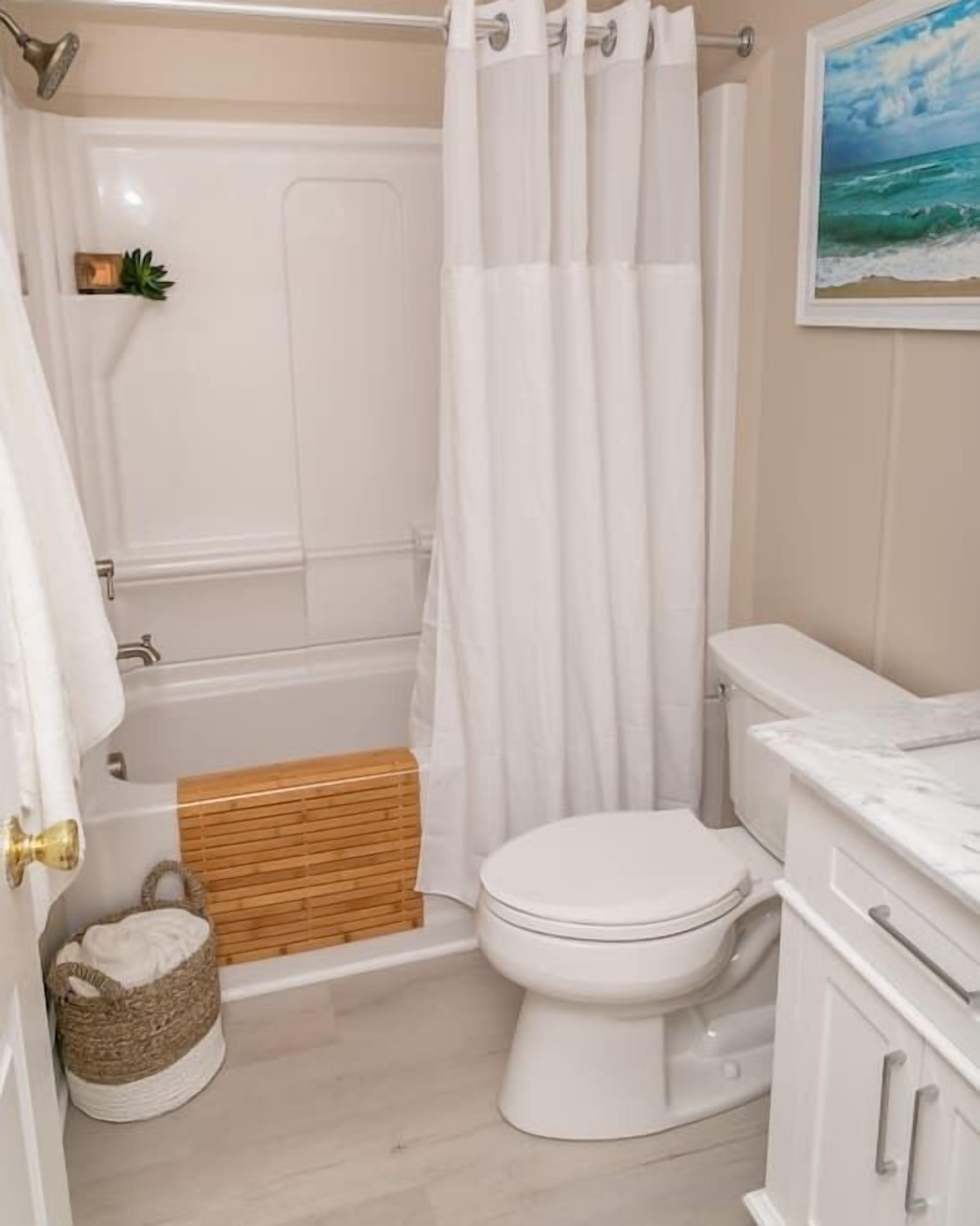 A bathroom with a bathtub, toilet, and a small wooden bench.
