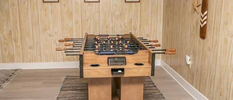 A foosball table in a room with wooden walls and framed artwork.