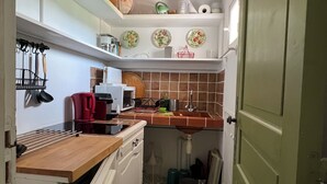 Uma cozinha compacta com armários brancos, bancada de madeira e porta verde.