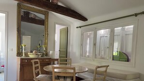 Uma sala de jantar com uma mesa redonda, quatro cadeiras, um armário de madeira e um espelho grande.