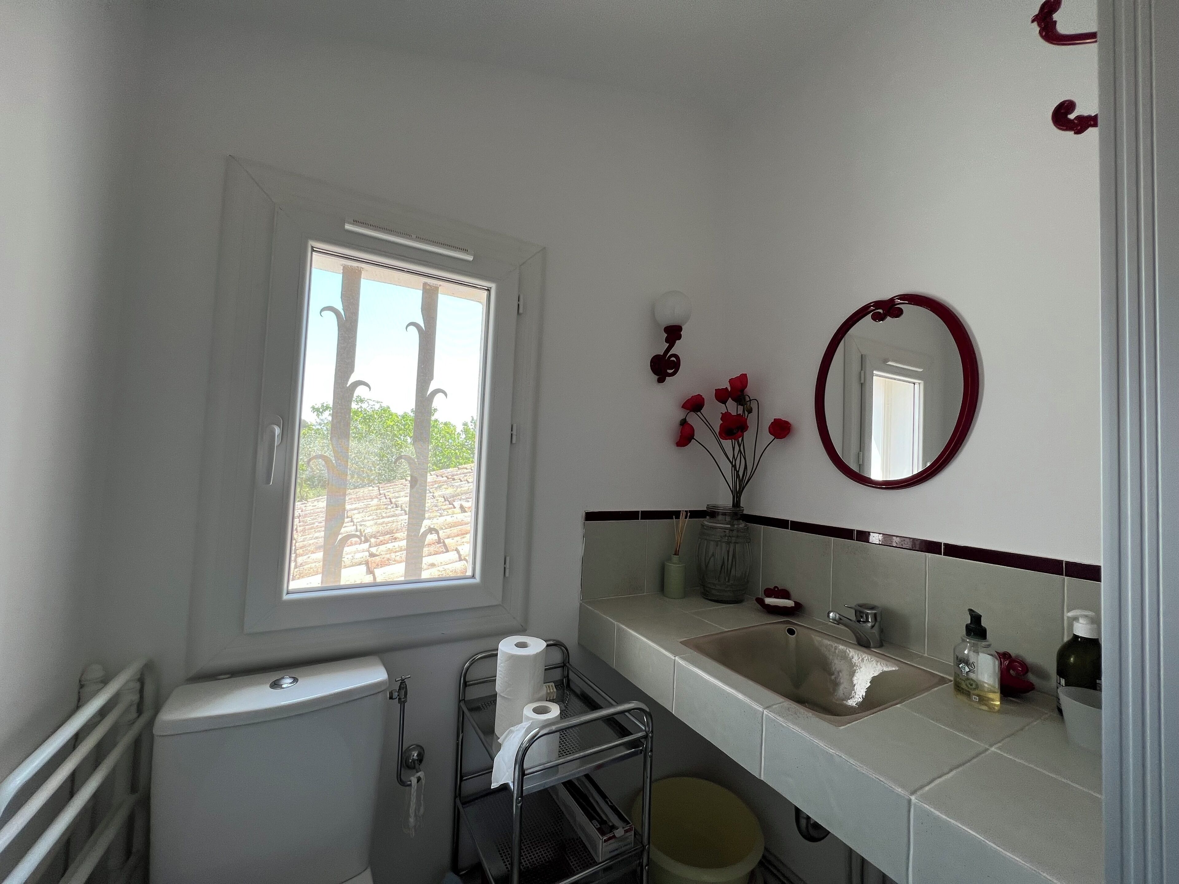 Uma casa de banho com sanita, lavatório e janela.