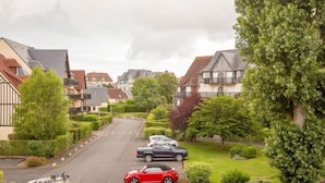 Une rue résidentielle bordée de maisons, de voitures garées et d’espaces verts.