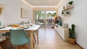 Un comedor moderno con una mesa blanca, sillas color turquesa y vistas a palmeras a través de la puerta de vidrio.