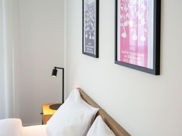 A hotel room with a bed, a nightstand, and two framed pictures on the wall.