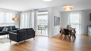 A modern living room with a dark sofa, a dining table with chairs, and a kitchen area. - LocTowers A4.8.2 by Interhome (Locarno)