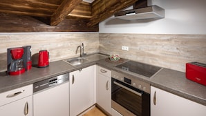 A modern kitchen with white cabinets, stainless steel appliances, and a wooden ceiling.