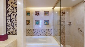 A modern bathroom with a glass-enclosed shower, a bathtub, decorative tiles, and a metal railing.