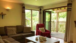 A cozy living room with a sofa, a red chair, a wooden coffee table, and a lamp. - Water Mill Vacations, Badgers Oak (Calbourne)