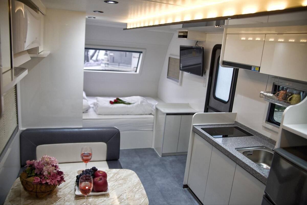 A compact kitchenette with a sink, stove, and window. A small dining area with a table and chairs is visible.