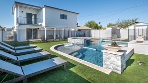 Ein modernes, zweistöckiges Haus mit Swimmingpool, Whirlpool und einer Terrasse mit Liegestühlen.