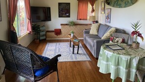 Una sala de estar con sofá, sillón, mesa de centro, televisor y una tabla de surf en la pared.