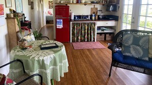 Una cocina acogedora con un refrigerador rojo, un comedor con mantel verde y un sofá de mimbre.