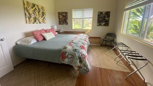 Un dormitorio con cama, una silla, un ventanal y obras de arte en las paredes.