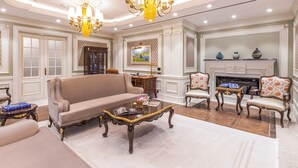 A luxurious living room with a beige sofa, ornate chandeliers, a fireplace, and classic furniture. - Wellness Park Hotels Turon (Samarkand)