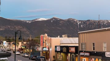 A street view with a mountain backdrop, featuring various shops including a pizza place and a Bayleaf restaurant.