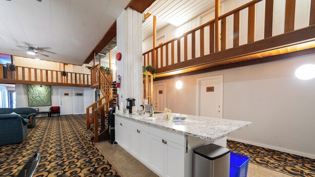 A spacious living area with a kitchen island, a staircase, and a patterned carpet. - Uptowner Hotel (Creston)