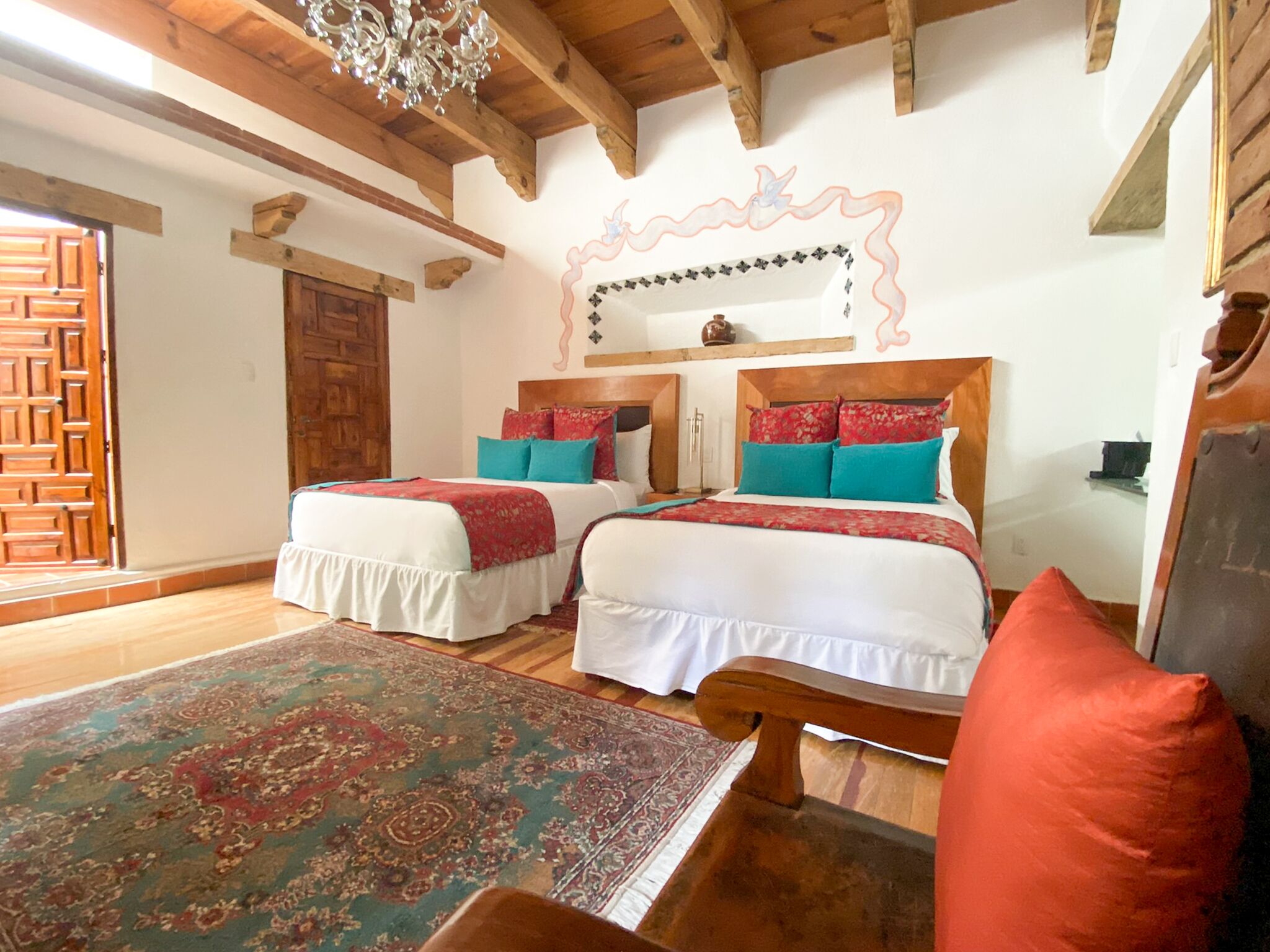 A traditional room with two beds, a wooden ceiling, and a patterned rug.