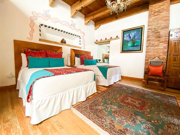 A double room with two beds, a large rug, a wooden ceiling, a mirror, and a painting. - Molino de los Reyes (Totolac)