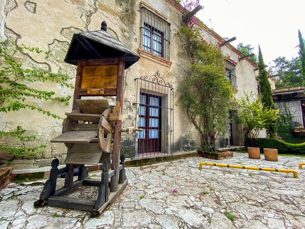 A rustic building with a stone facade, wooden steps leading to a door, and a water pump.
