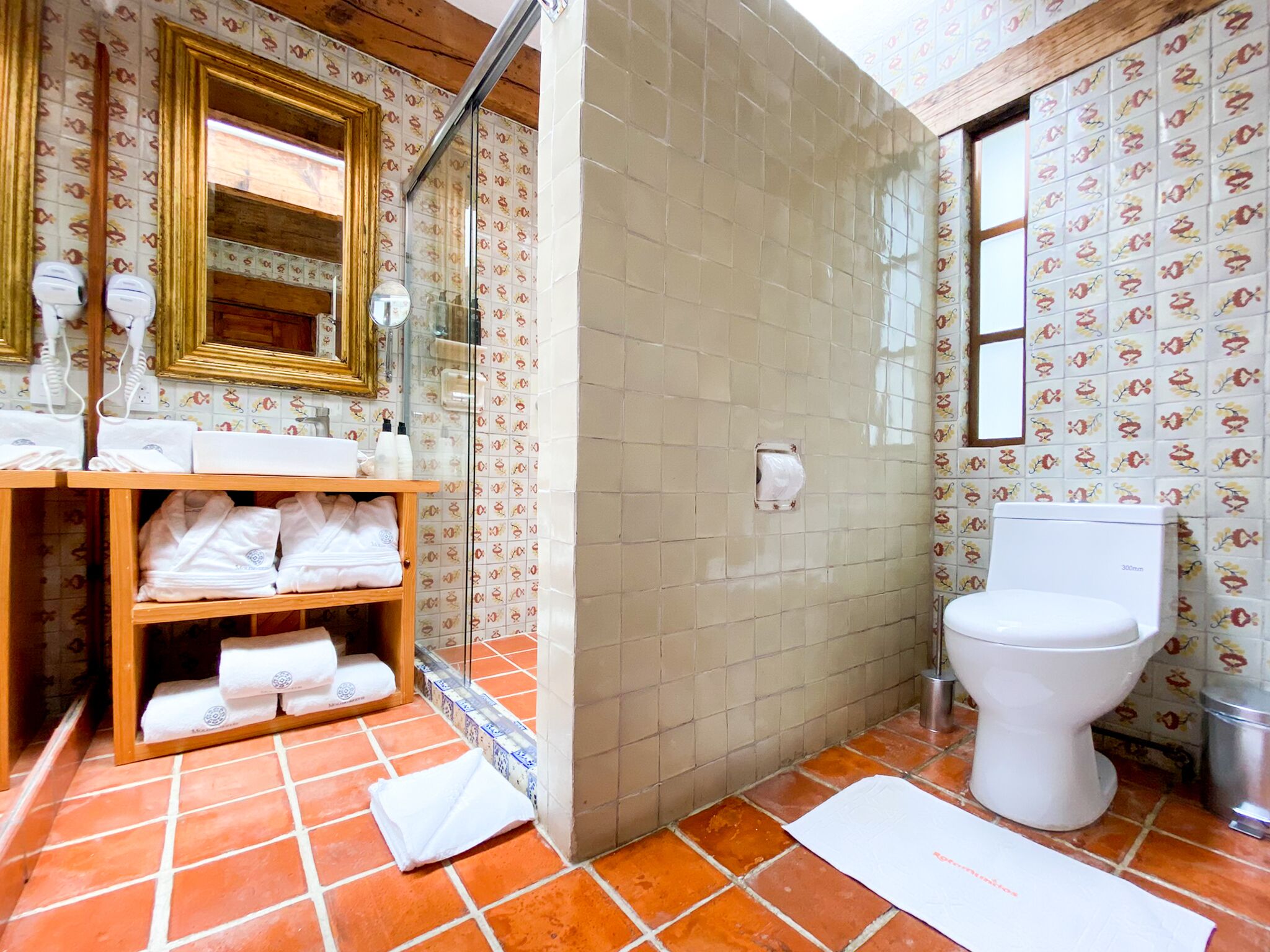 A bathroom with a shower, toilet, and a shelf with towels.