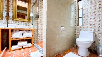 A bathroom with a shower, toilet, and a shelf with towels.