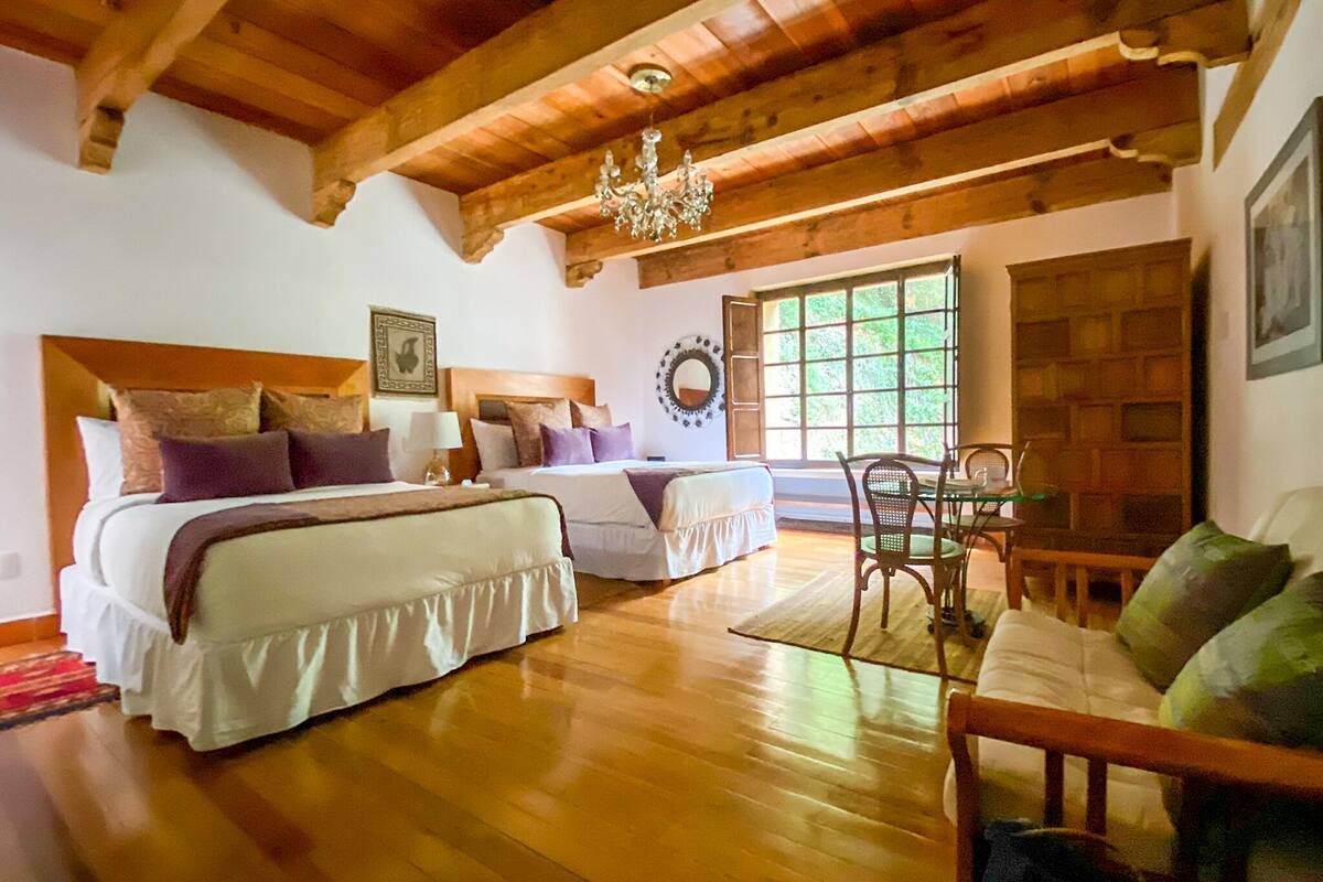 A wooden cabin-style bedroom with two beds, a chandelier, and a dining area.