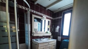 Un baño con ducha, lavamanos y espejo.