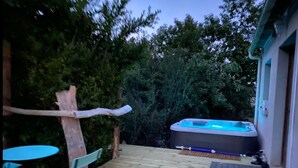Una terraza de madera con un jacuzzi, una mesa y sillas.
