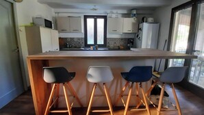 Una cocina moderna con una isla central, taburetes de bar y un ventanal que proporciona luz natural.