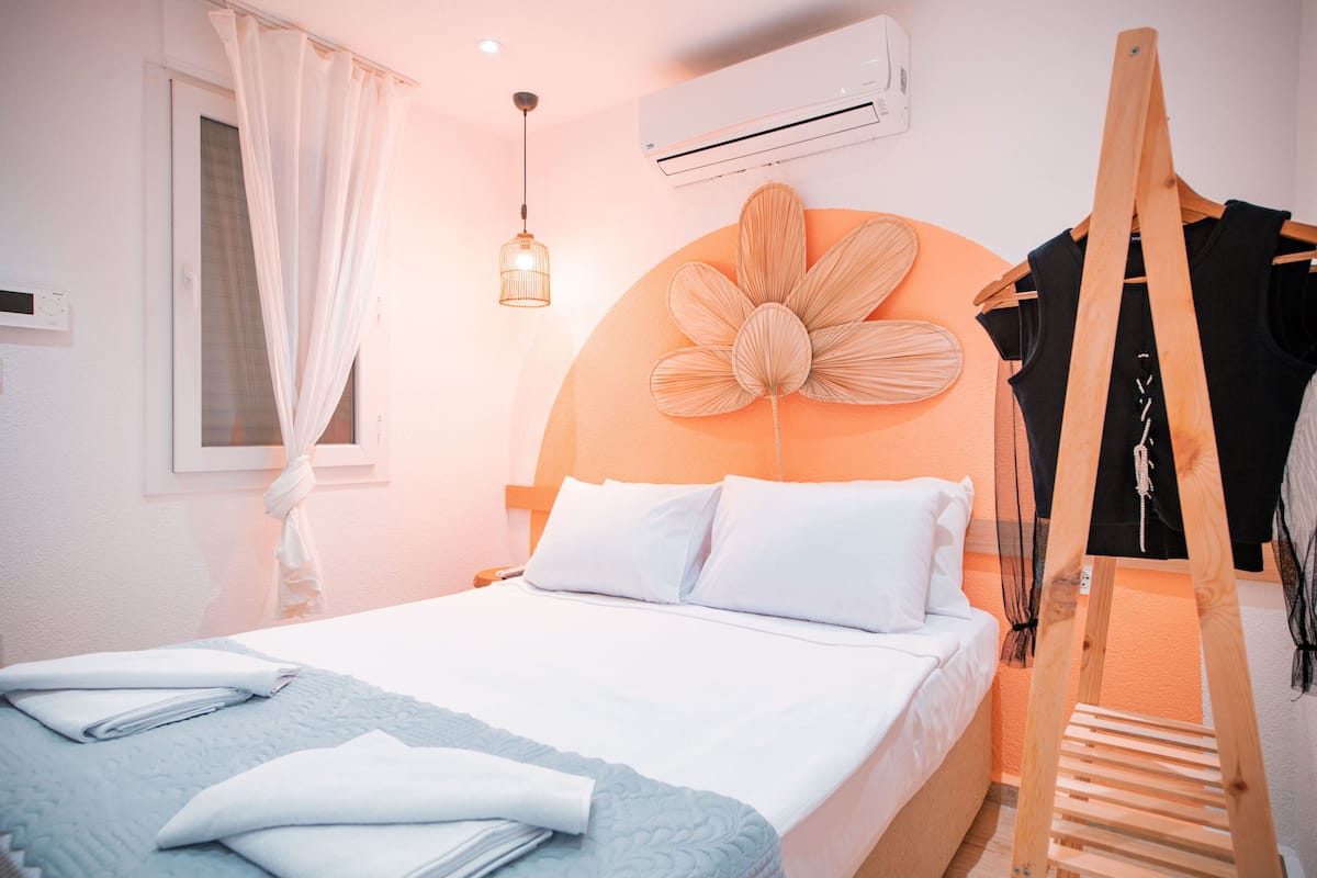 A neatly made bed with white linens, a wooden ladder, and a large flower-shaped wall decoration.