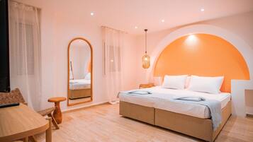 A modern bedroom with a large bed, a small table, a chair, and a mirror.
