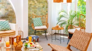 A modern interior with wicker furniture, a glass table, and a view of greenery outside. - MARE MARIN BOUTIQUE HOTEL (Bodrum)