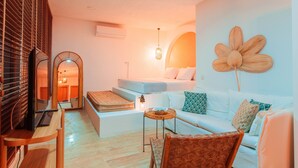 A modern living room with a sofa, a wicker chair, a small table, and a large decorative flower on the wall. - MARE MARIN BOUTIQUE HOTEL (Bodrum)