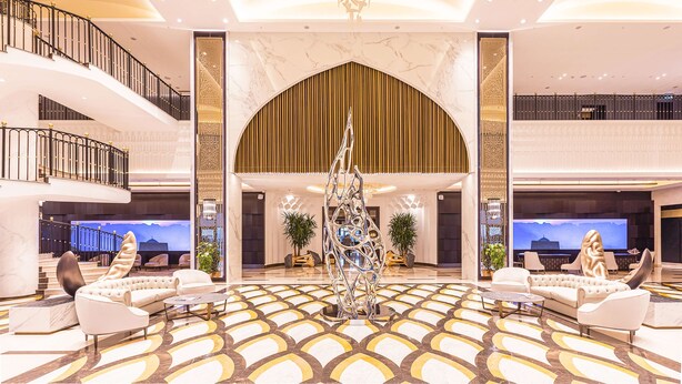 A spacious lobby with a central chandelier, a modern sculpture, and a patterned floor. - Hilton Samarkand Regency (Samarkand)