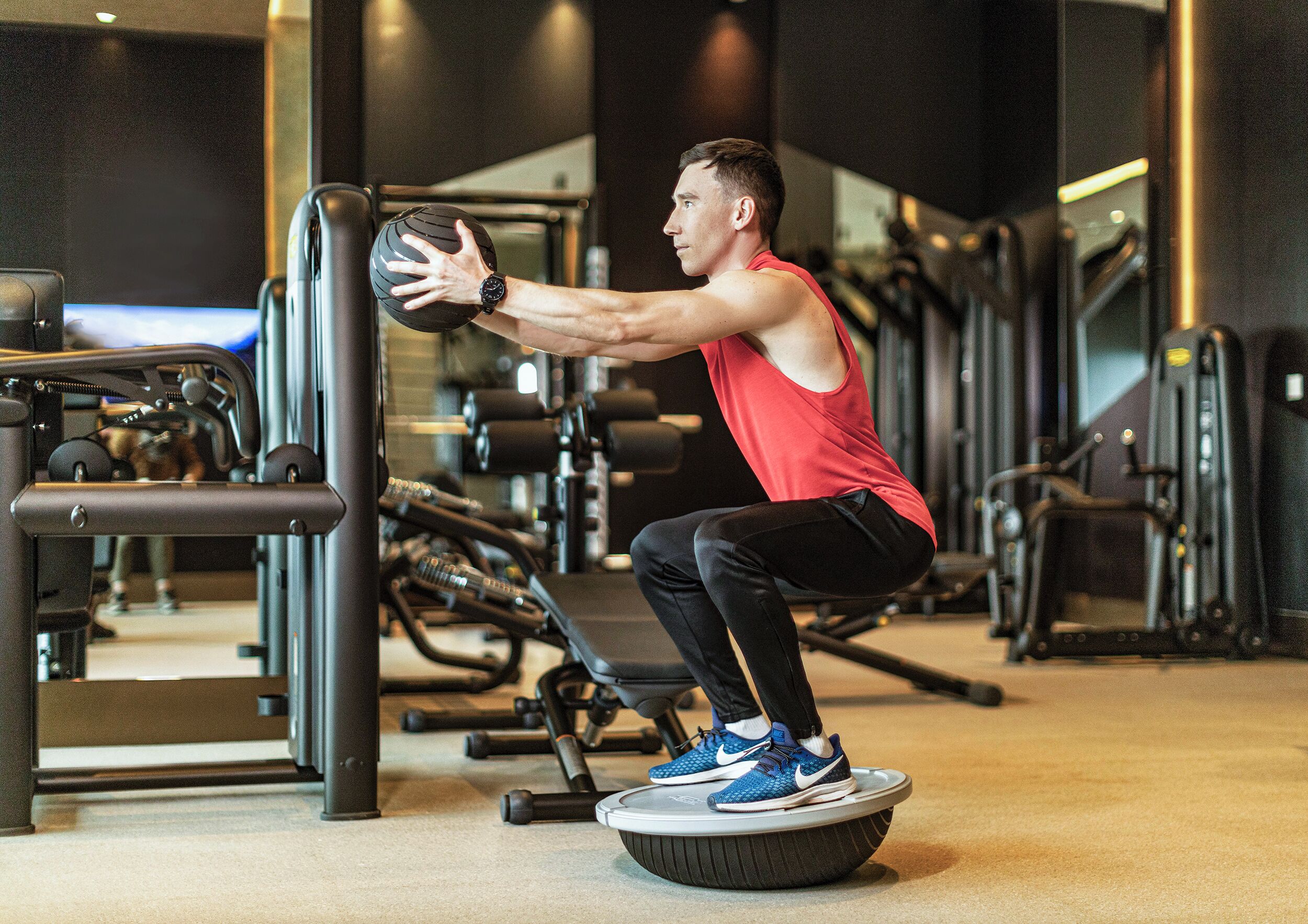 A gym with exercise equipment, including a squat station and weight machines.