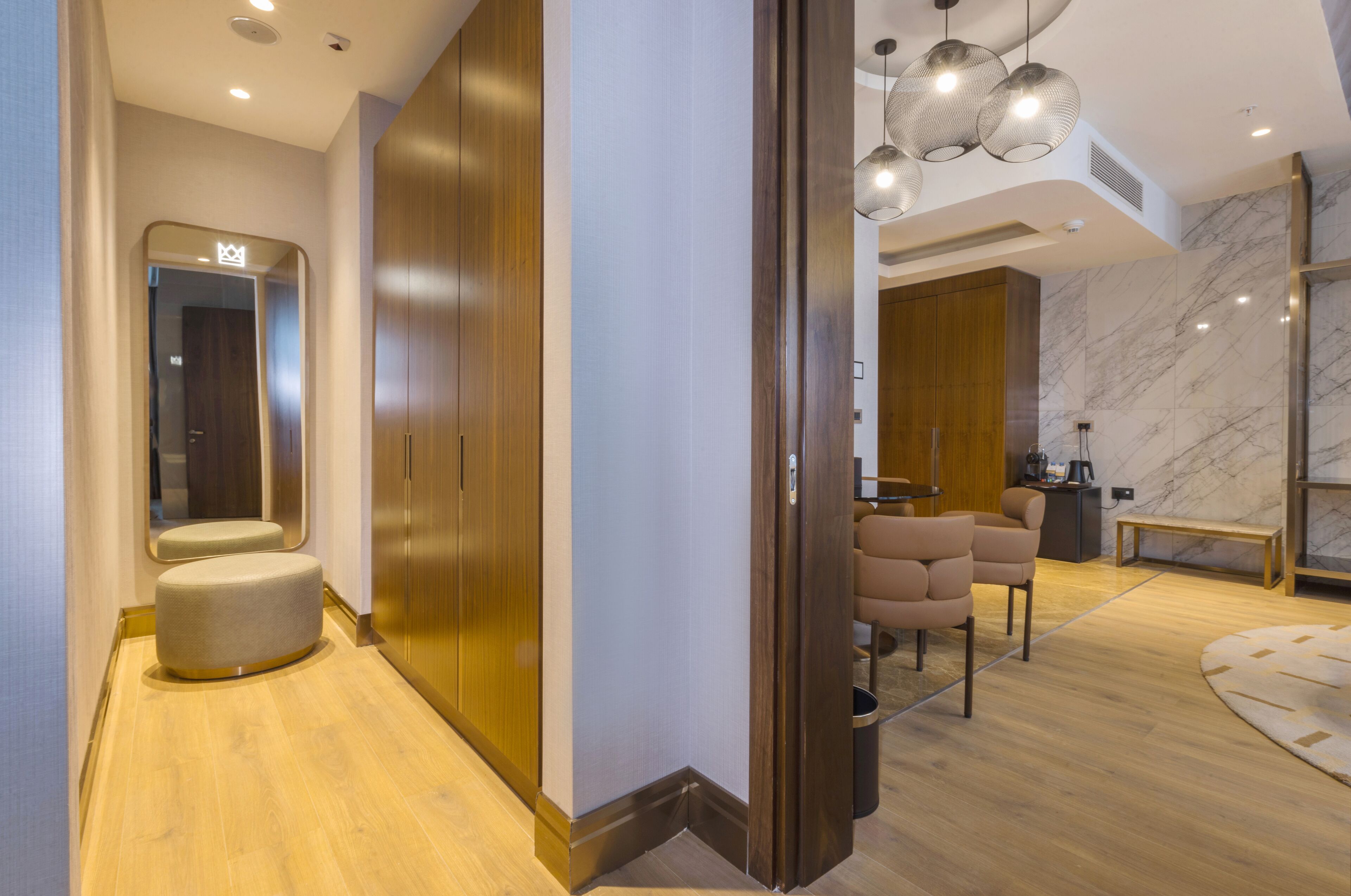 Un hall d’hôtel moderne avec un plancher en bois, un espace salon circulaire et un mur en marbre.