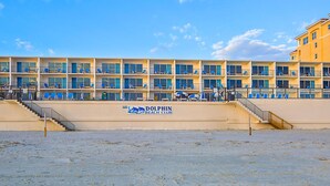 Edificio del Dolphin Beach Club con varios balcones y un primer plano arenoso.