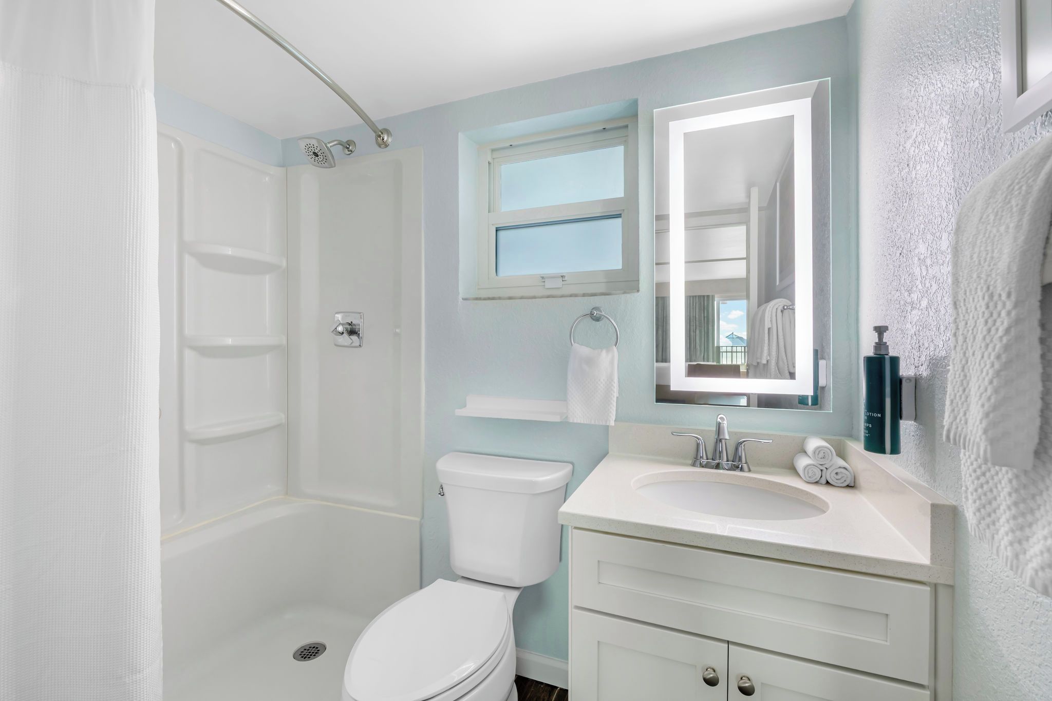 A bathroom with a shower, toilet, sink, and a mirror.