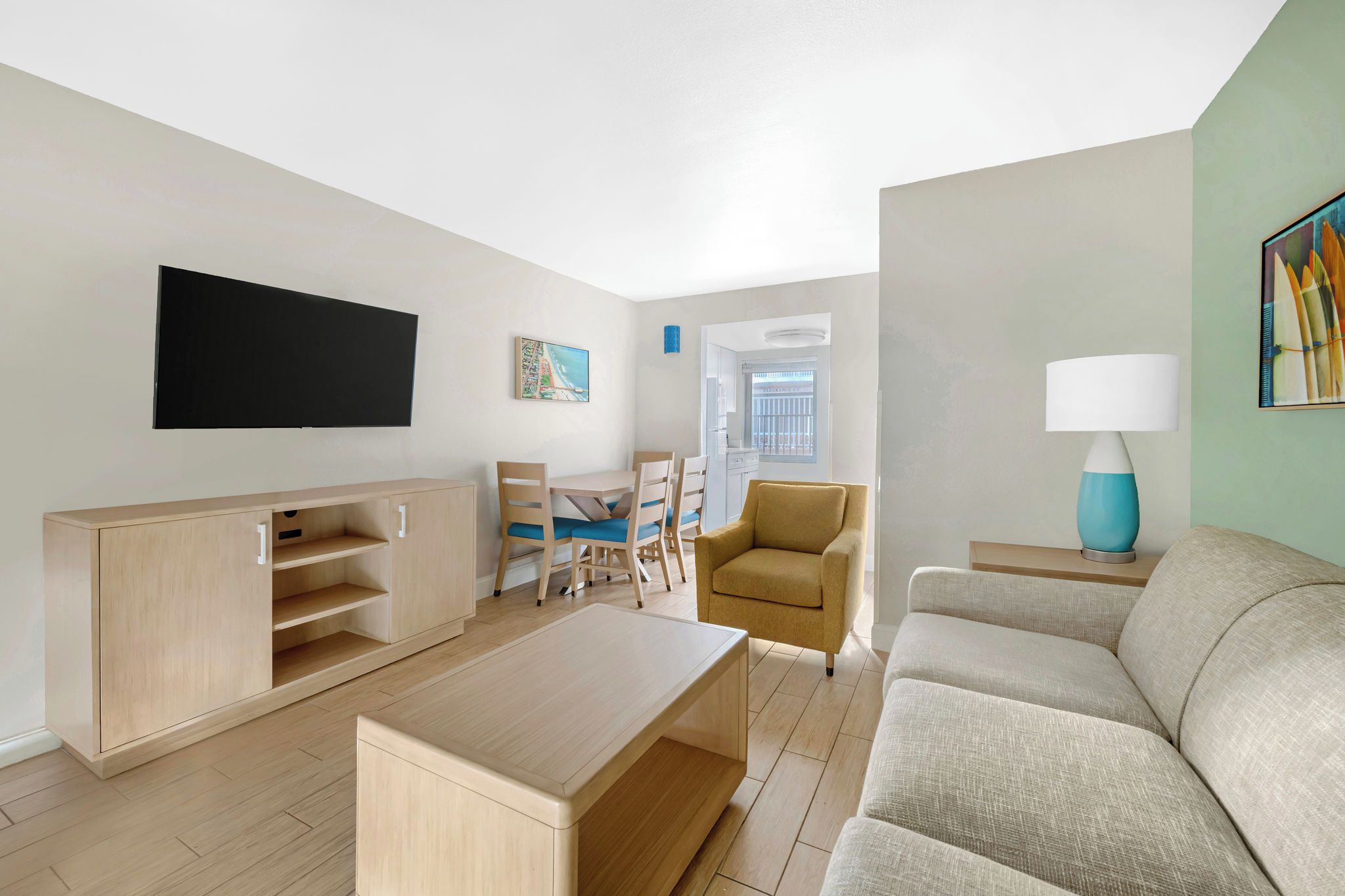 Ein modernes Wohnzimmer mit Flachbildfernseher, einer Couch, einem Couchtisch, einem Essbereich mit Stühlen und einer Lampe.
