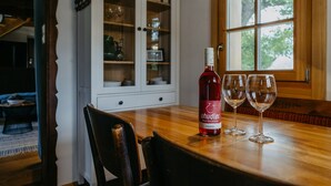 A wooden dining table with a bottle of wine and two glasses.