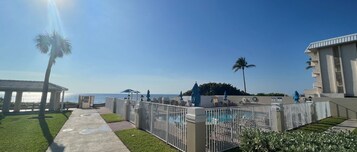 Una piscina al aire libre, sombrillas, sillones reclinables de piscina