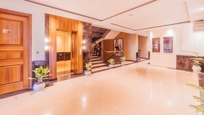 A spacious lobby with a polished floor, a staircase, and potted plants. - The Ramayana Hotel Ayodhya (Faizabad)