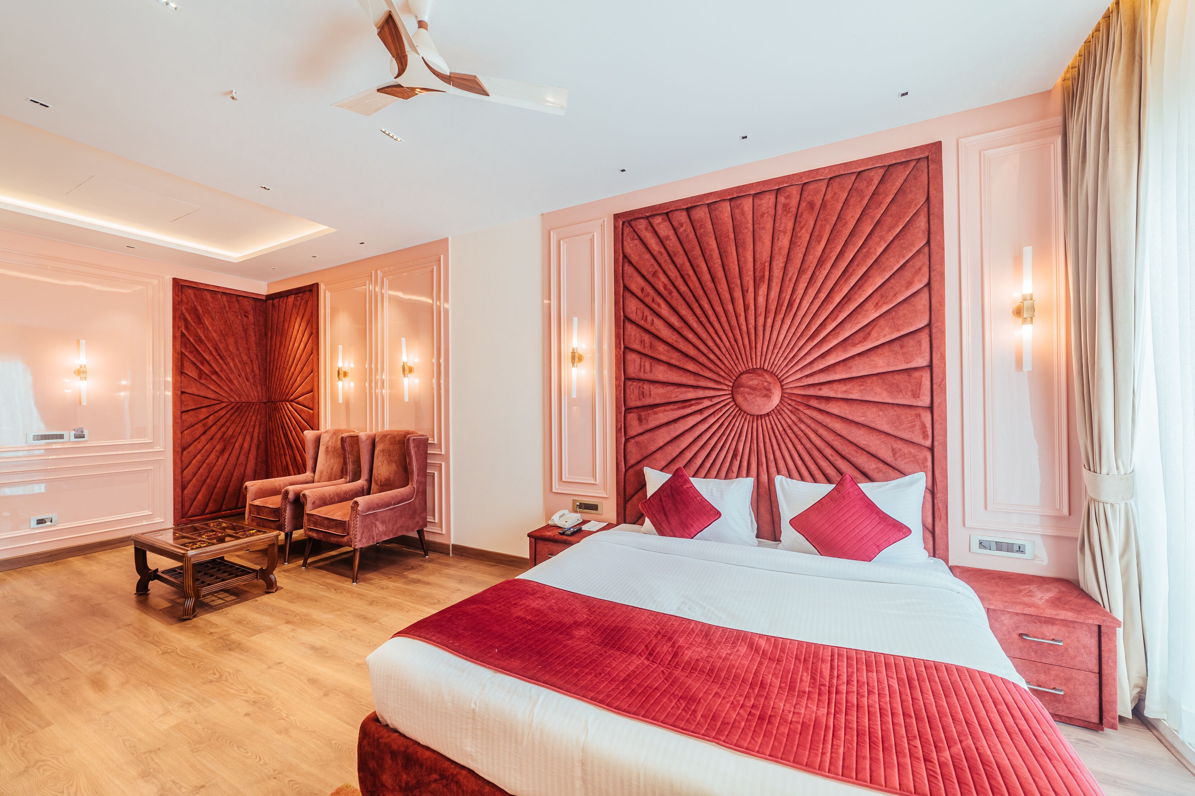 A spacious bedroom with a large bed, a wooden nightstand, a chair, and a ceiling fan.